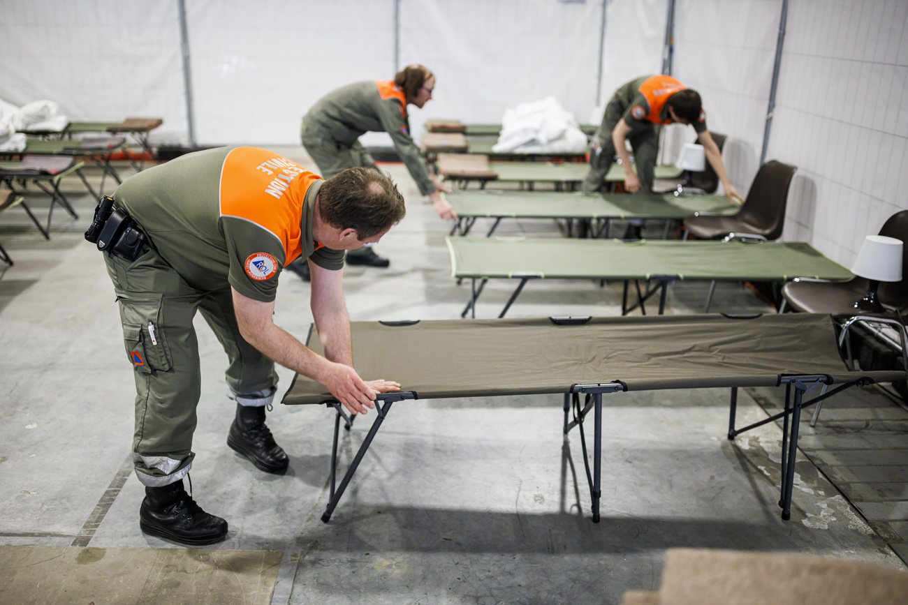 Homens instalando camas temporárias no centro de refugiados