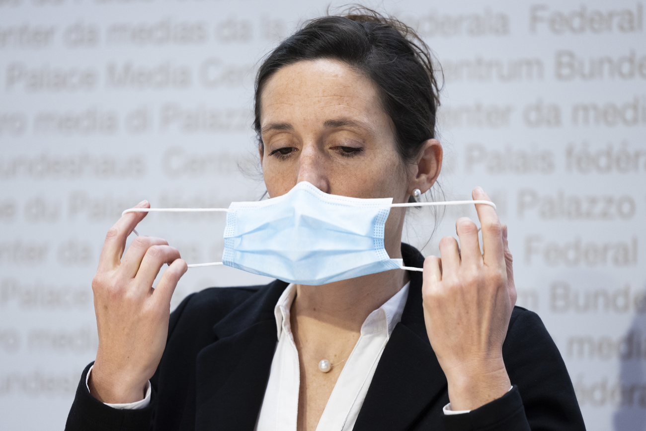 woman putting on surgical mask at press conference