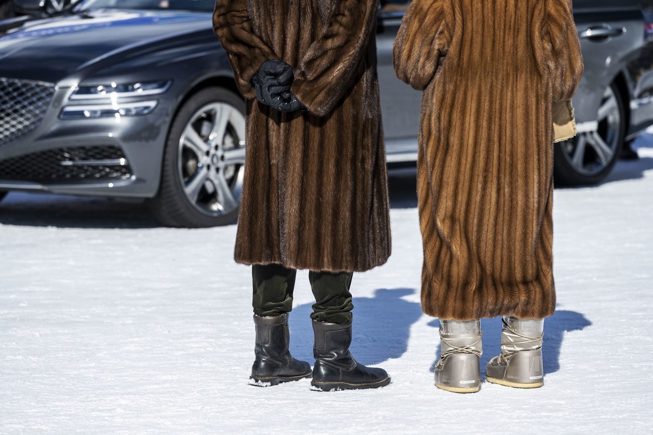 people in fur in front of car