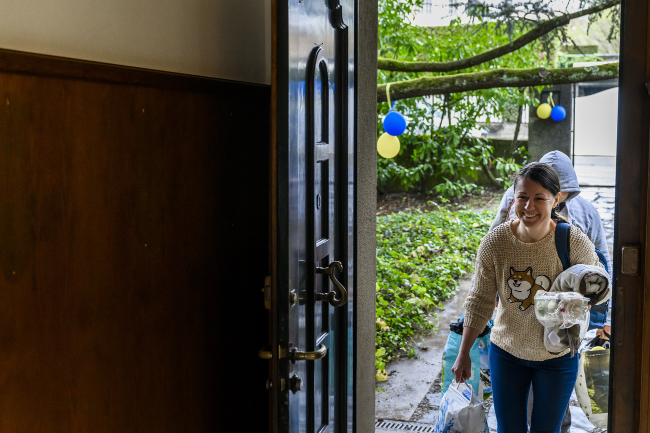 mujer entrando en una casa con una maleta y un juguete en la mano