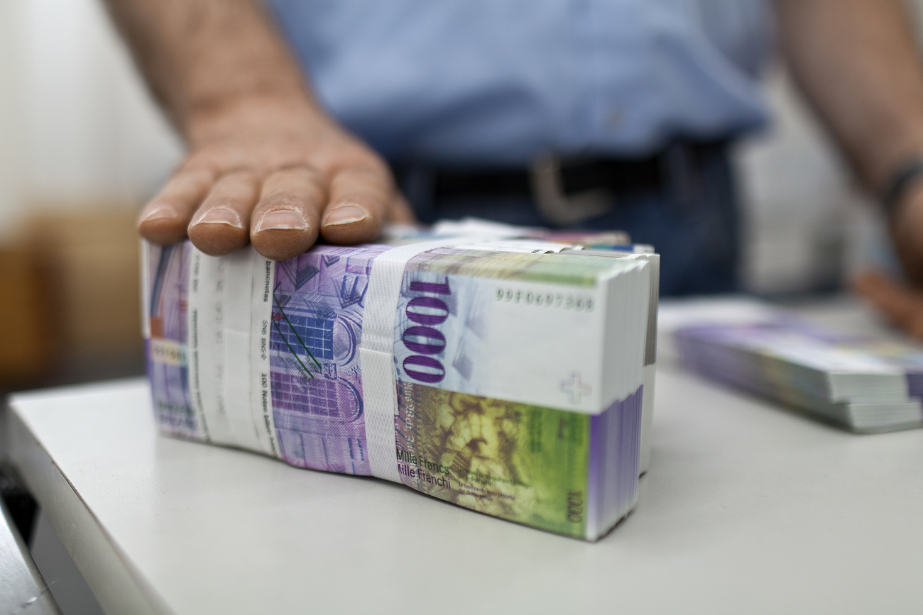 Hand rests on pile of CHF1,000 bank notes