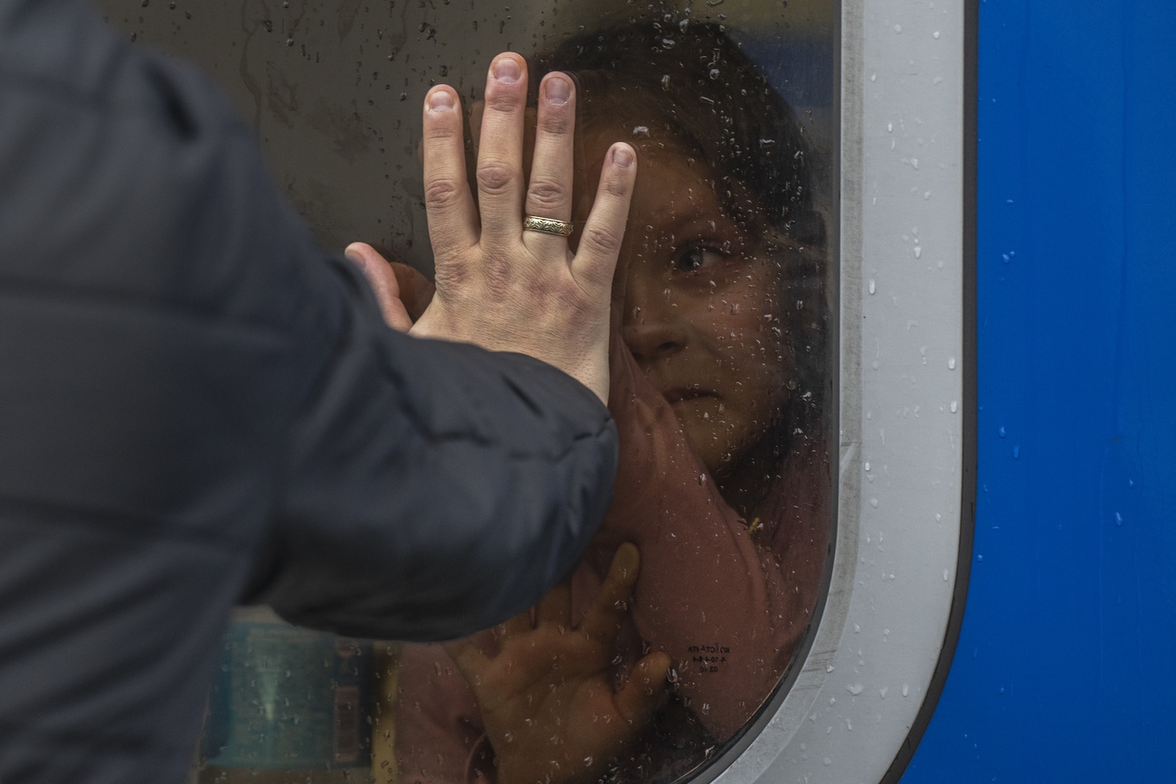 طفلة داخل عربة قطار تودع رجلا يضع يده على زجاج النافذة من الخارج
