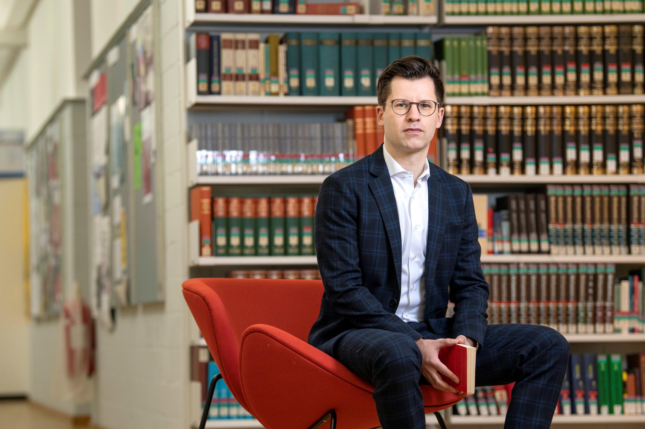 Homme assis devant une bibliothèque