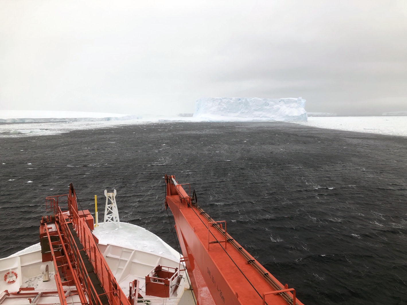 Ship weathering behind iceberg