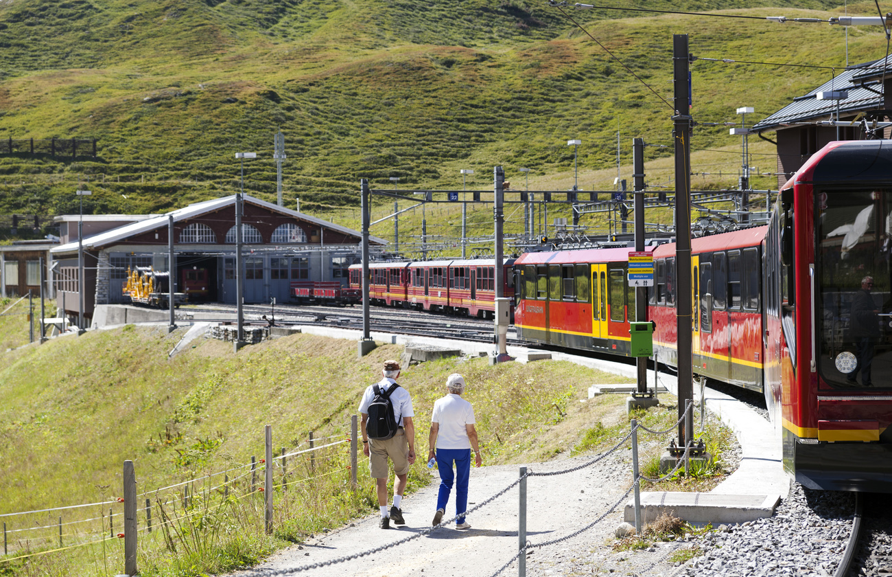 Una pareja mayor caminando cerca de una estación de tren en las montañas