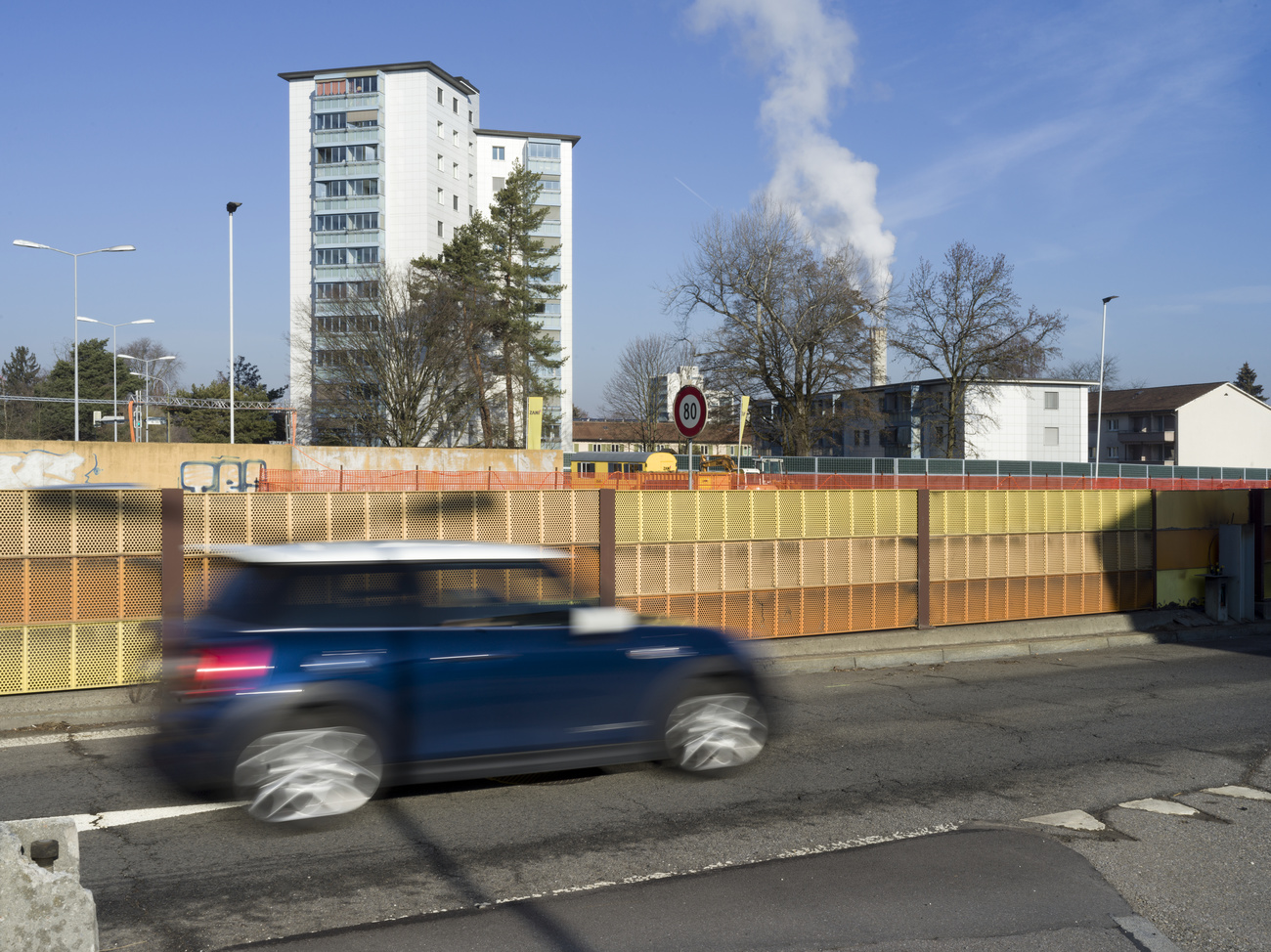 Car drives past factor chimney and houses