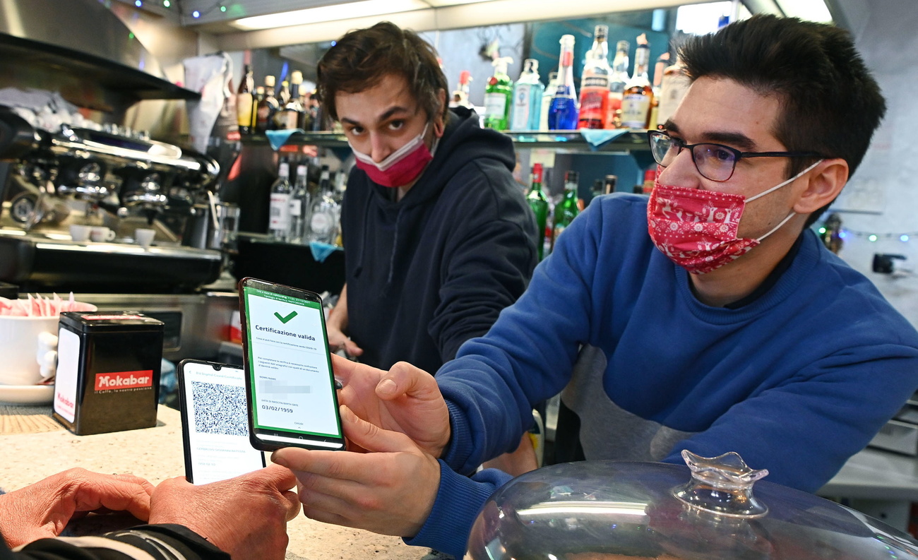 due persone con mascherina dietro a un bancone, uno di loro scannerizza un green pass