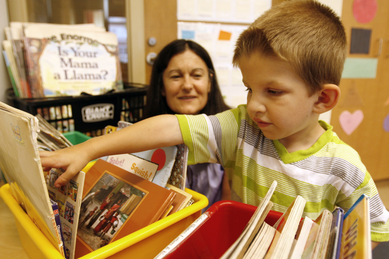 bambino di pochi anni cerca libro in scatola con diversi volumi