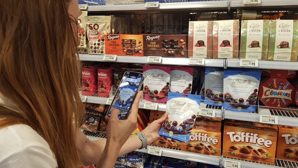 EIne Frau scannt ein Produkt mit ihrem Handy