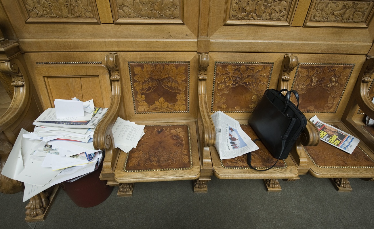 Banco no parlamento com jornais e mala de mão