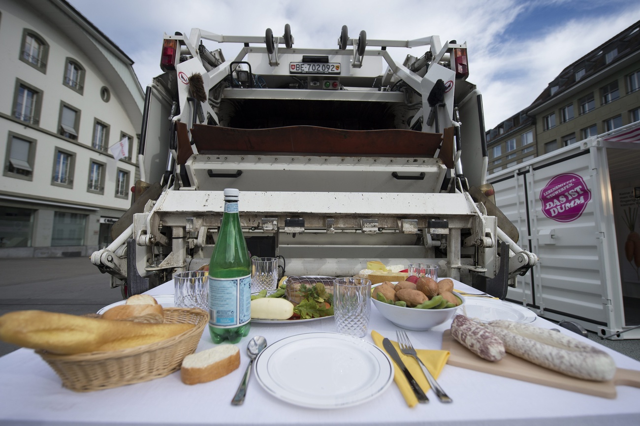 Una tavola imbandita con dietro un camion della spazzatura.