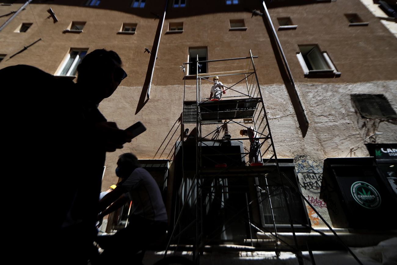 impalcatura su un edificio. operai e passanti in controluce