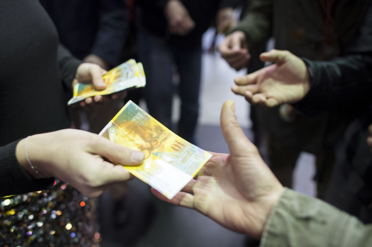 Person handing out Swiss bank notes