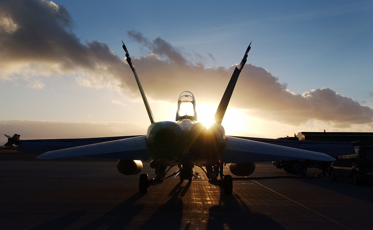 Un F/A 18 a terra fotografato al tramonto.