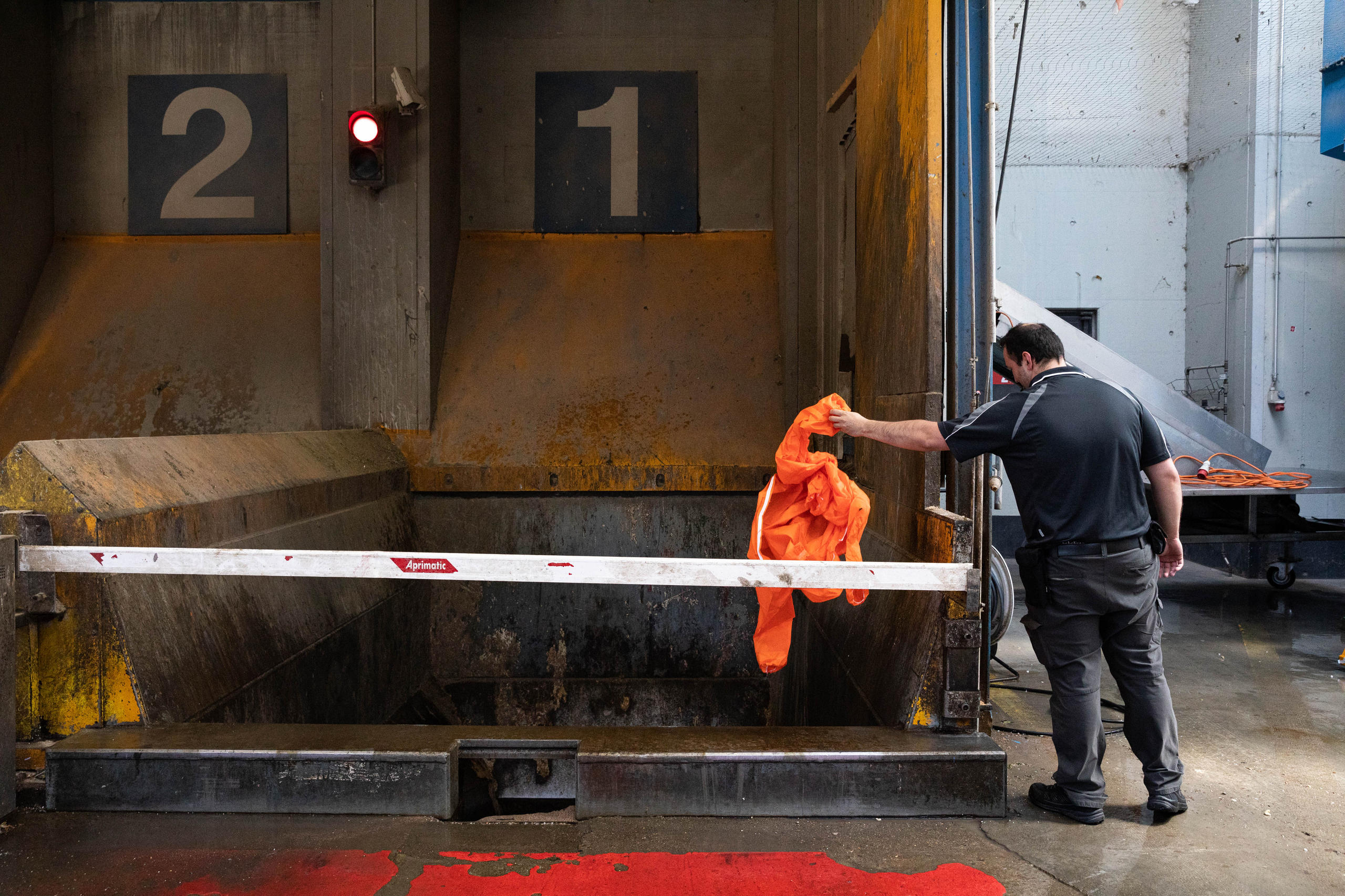 Un hombre arroja una vestimenta anaranjada a la basura.