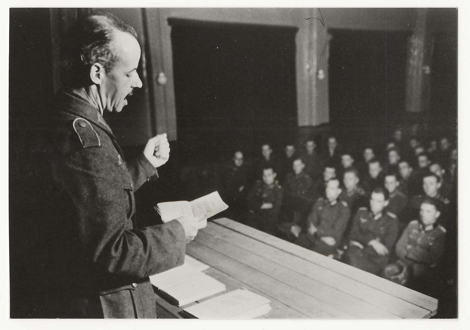 Anacker en estrado ante auditorio de soldados.