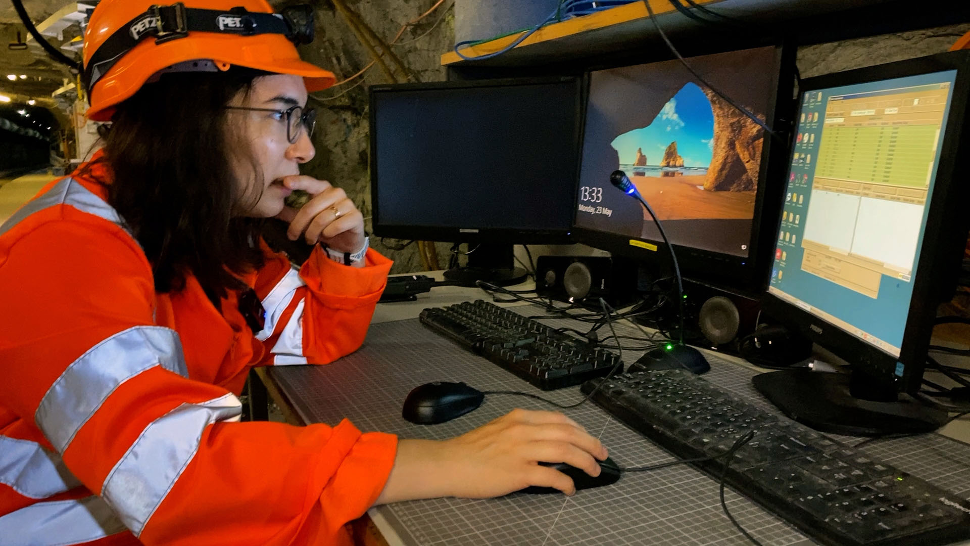 Eine Frau checkt in einem unterirdischen Felslabor auf einem Bildschirm einige Einstellungen.