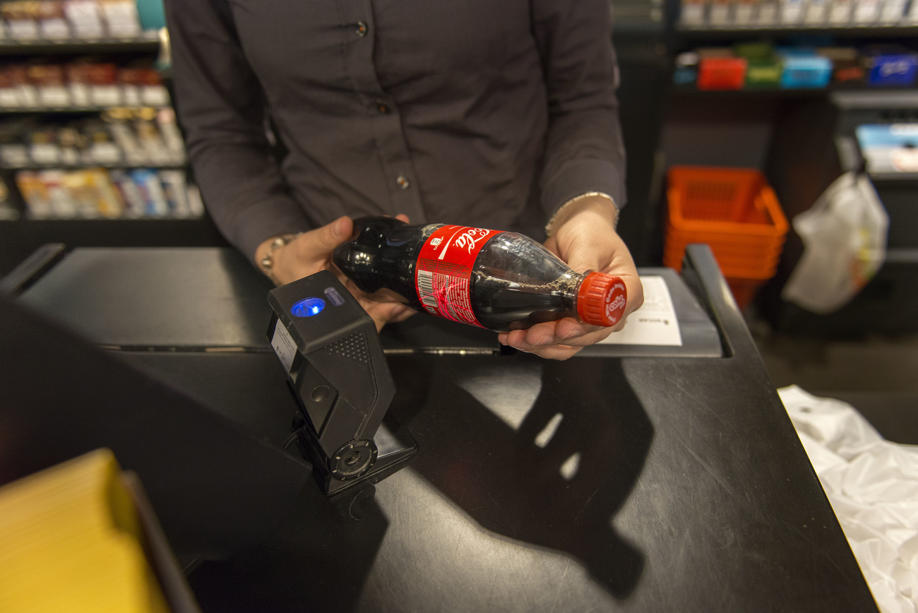 persona alla cassa scannerizza una bottiglietta di coca cola