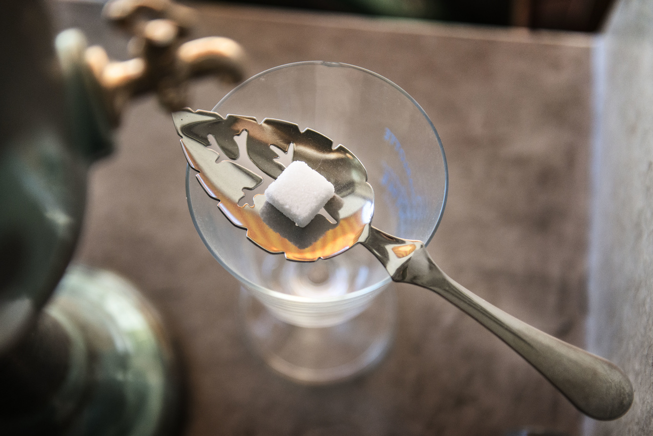 cucchiaio d argento forato contenentte zolletta di zucchero appoggiato sopra un bicchiere