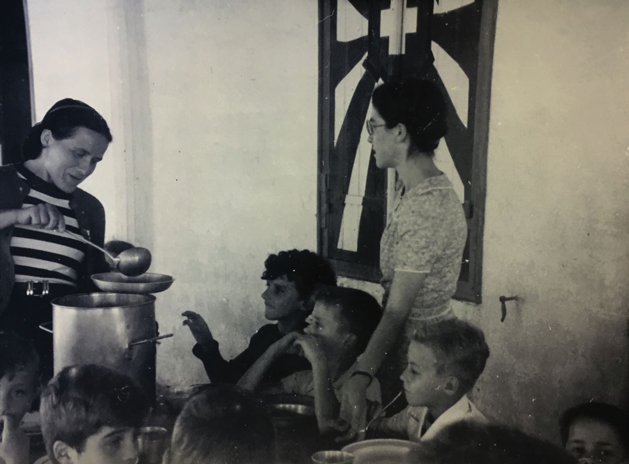 woman serving soup to children