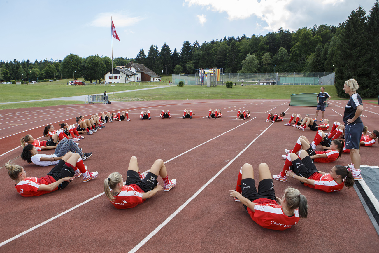 atlete in posizione da addominali sdraiate in cerchio su una pista di atletica