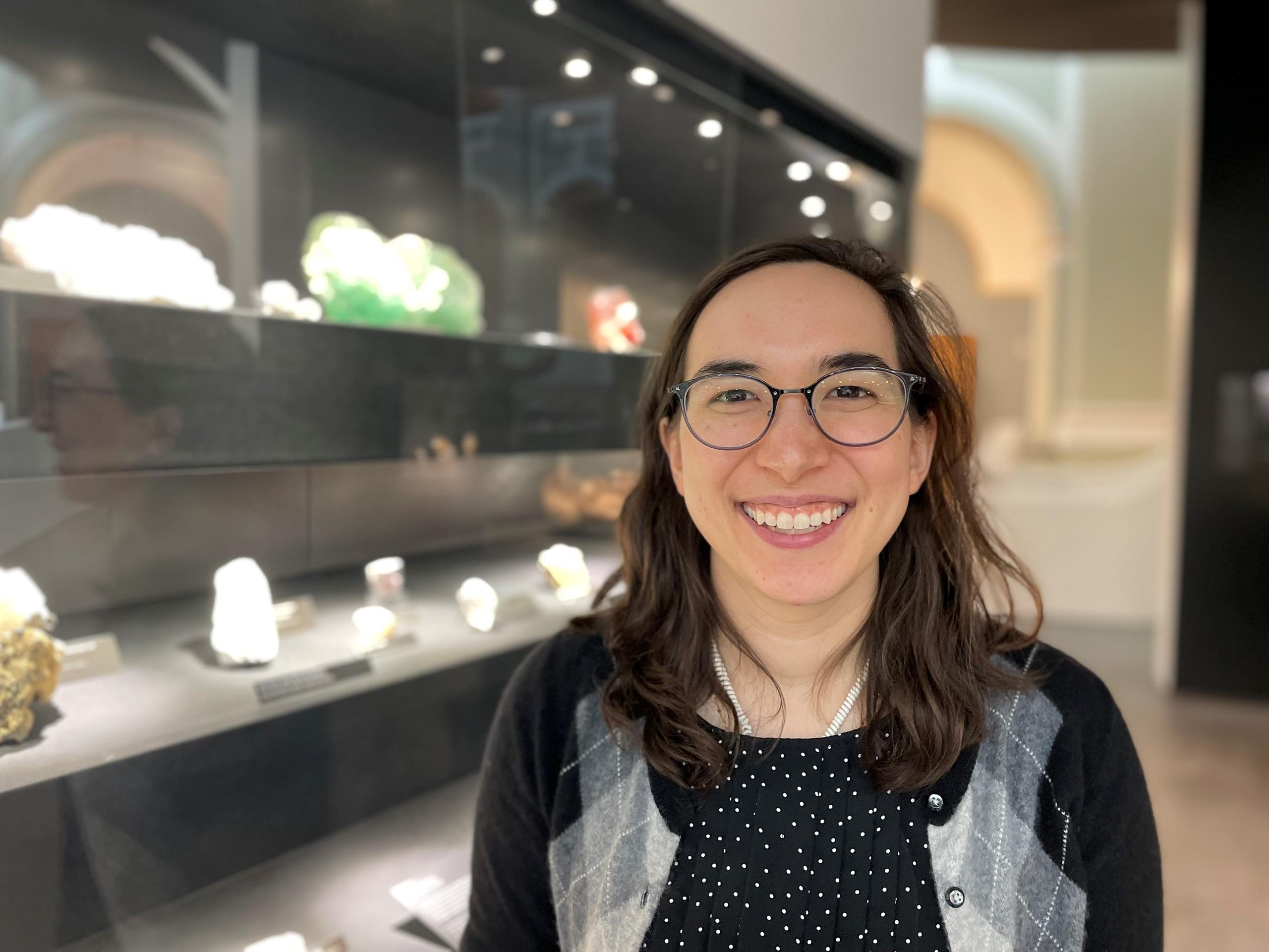 Femmes souriante avec des lunettes devant une collection de cristaux