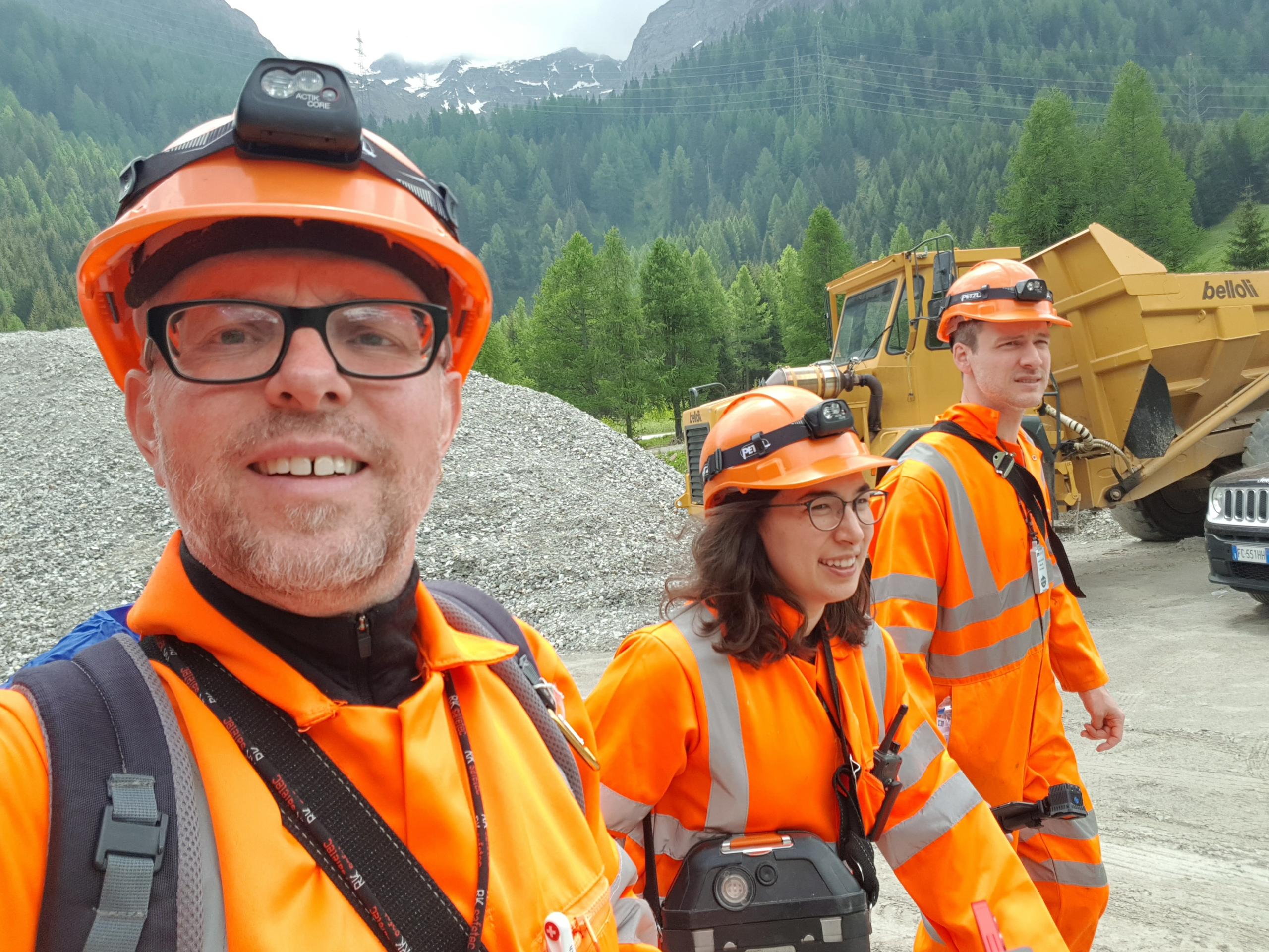 Trois personnes casquées et équipées sortant des entrailles d une montagne.
