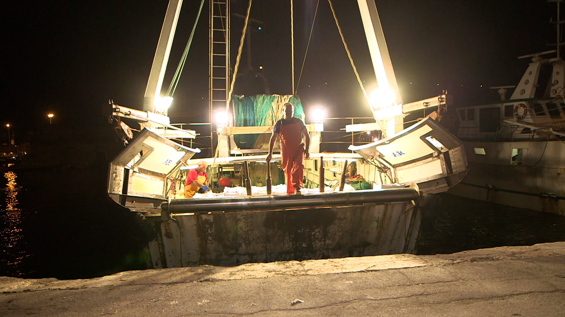 pescatore sbarca da peschereccio illuminato. è notte