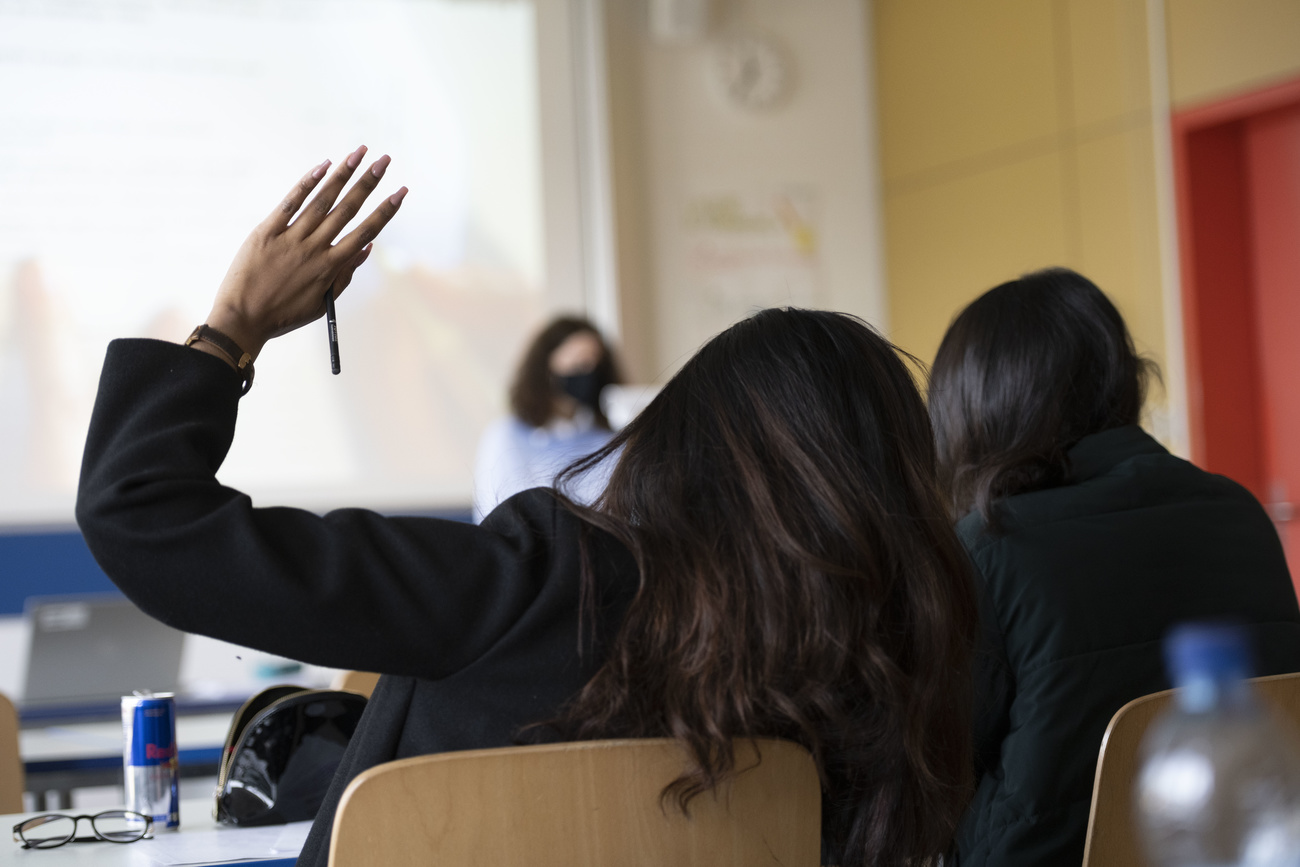 girl puts hand up in classroom.