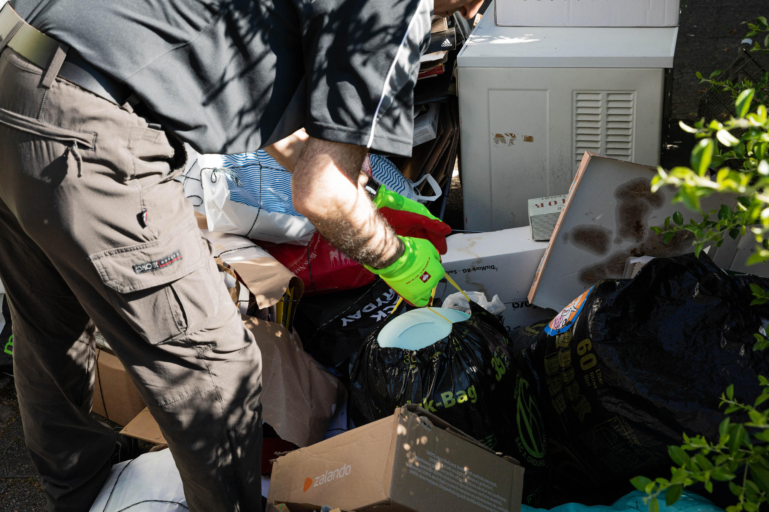 Un hombre con guantes hurga entre la basura.