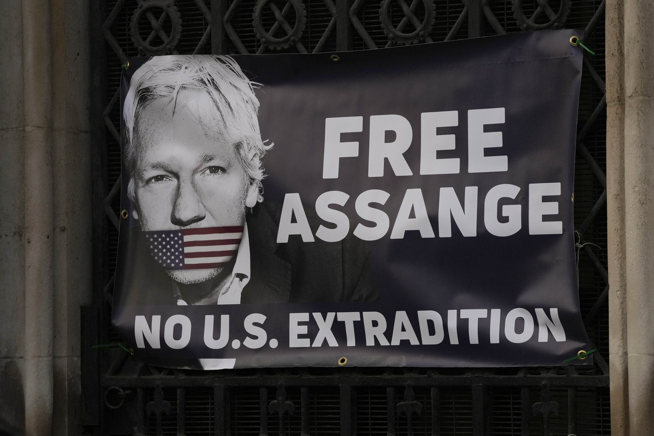 Un manifesto con Assange inbavagliato con una bandiera statunitense.