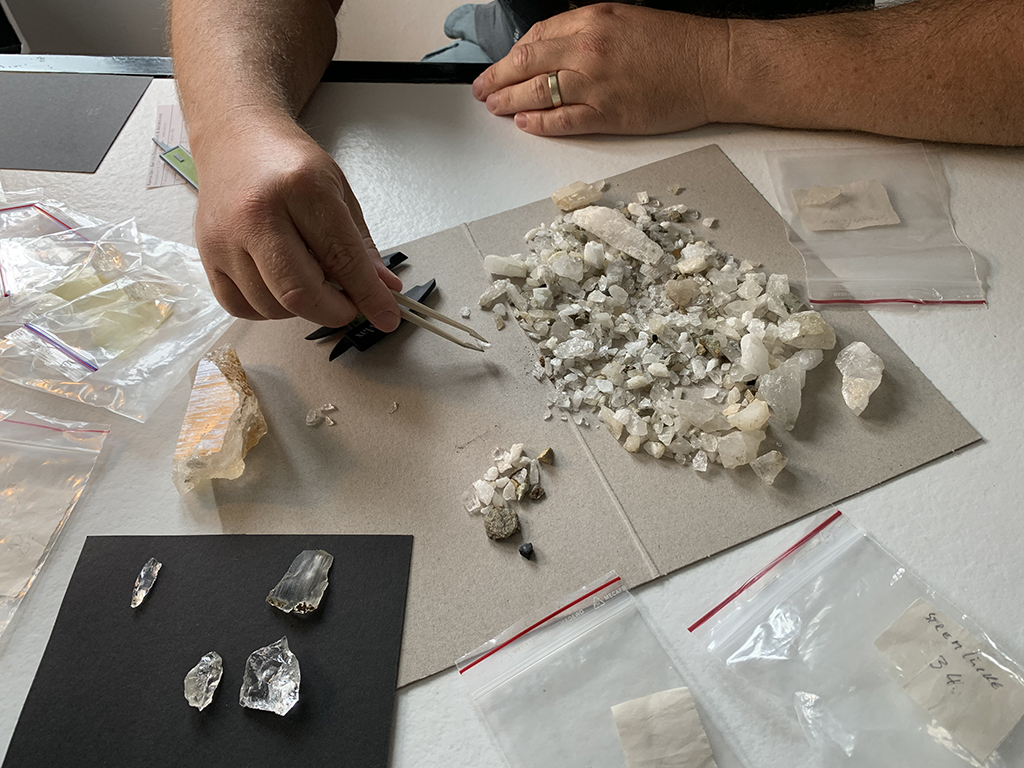 Un homme trie des fragments de roche à la pince à épiler