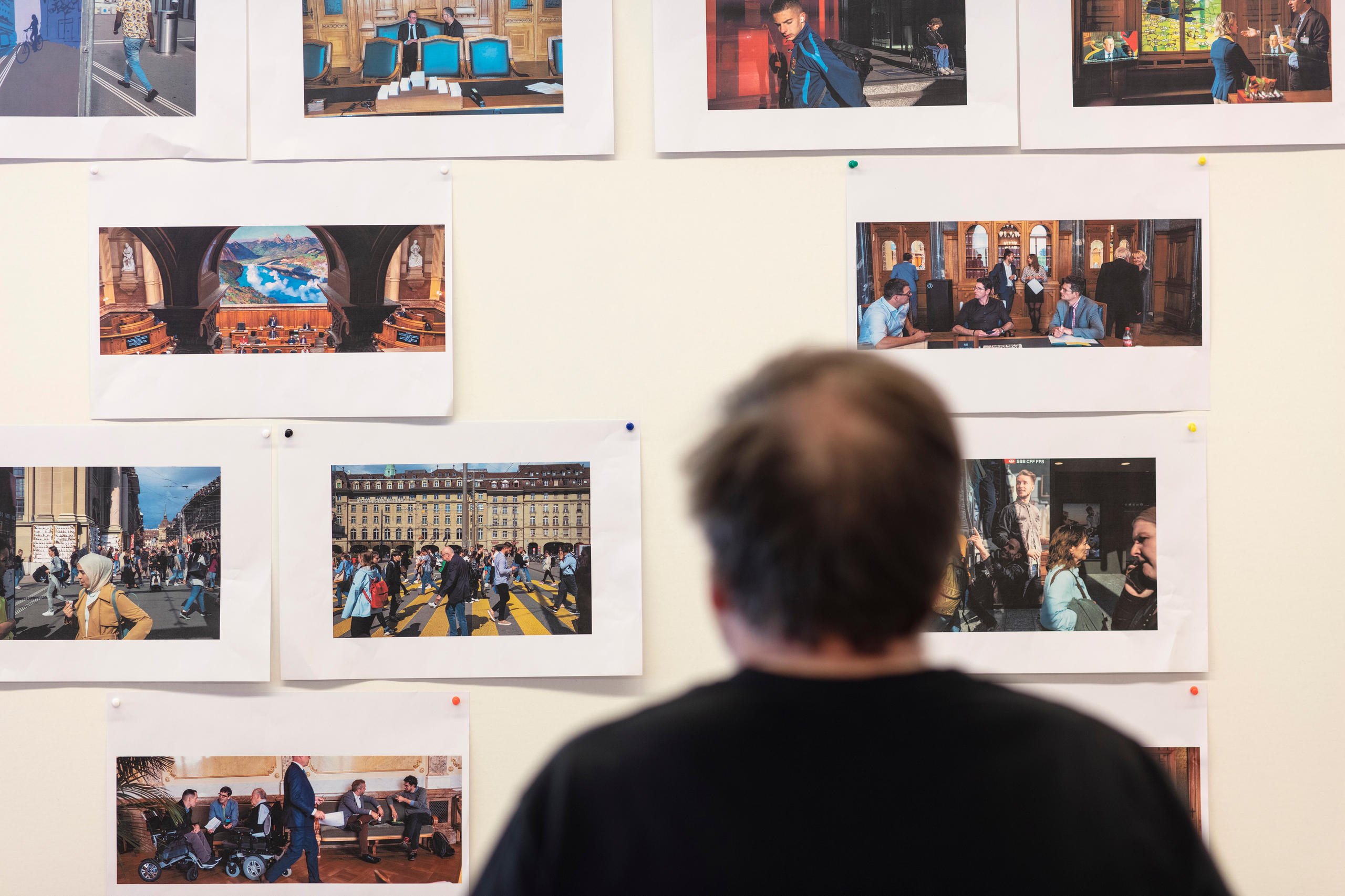 Alex Webb étudie des photos accrochées au mur.