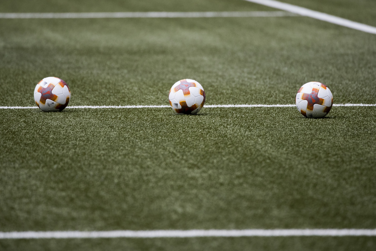 Three footballs on a pitch