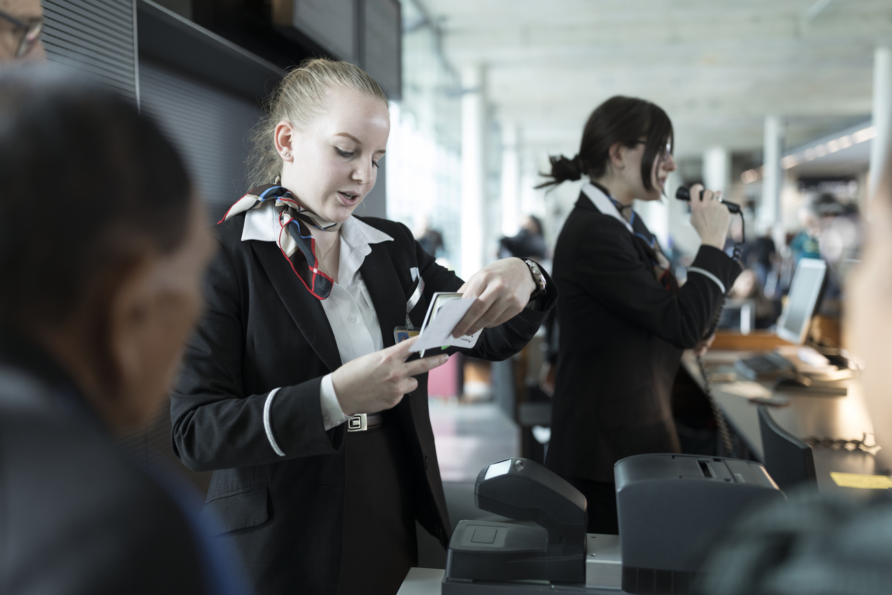 A Swissport employee checks the passports and boarding passes of the passangers