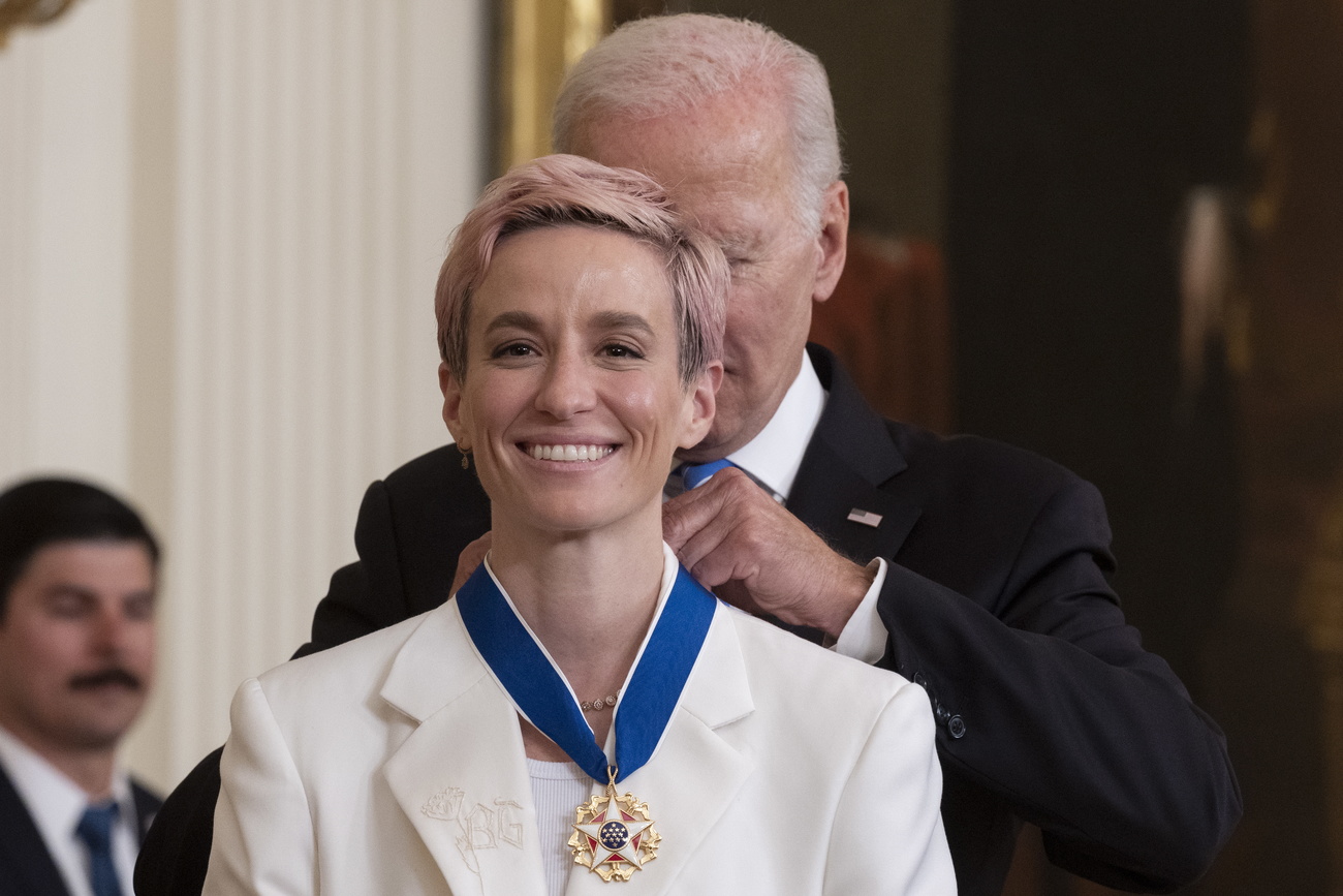 El presidente de EE UU, Joe Biden, coloca una medalla a Megan Rapinoe.