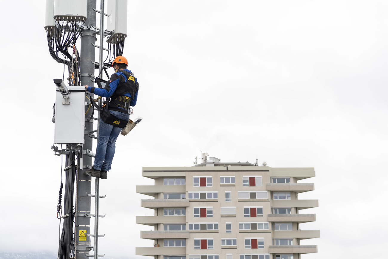 Un hombre, subido en un poste, trabaja con cables de conexión.