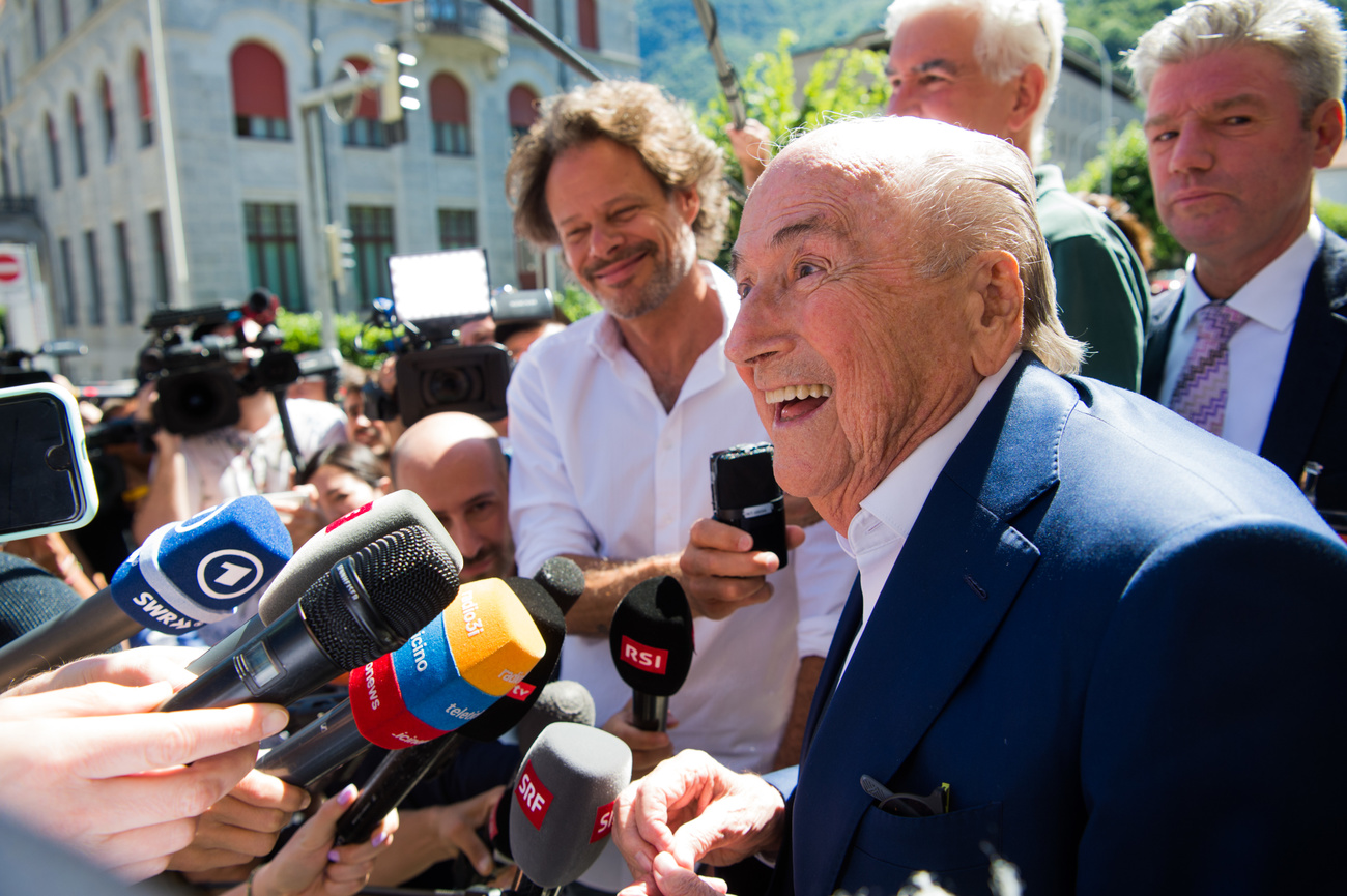 A smiling Joseph Blatter speaks to reporters outside of the courthouse following his acquittal