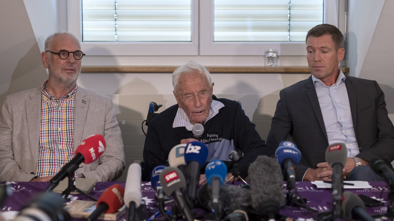 tre uomini seduti a un tavolo dietro a dei microfoni