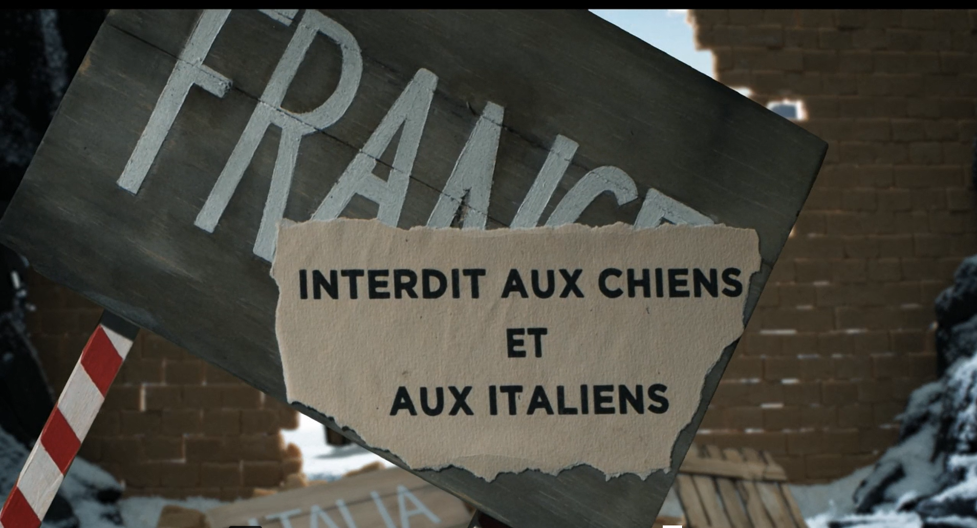 cartello cons critta FRANCE coperta da un foglio con scritta INTERDIT AUX CHIENS ET AUX ITALIENS