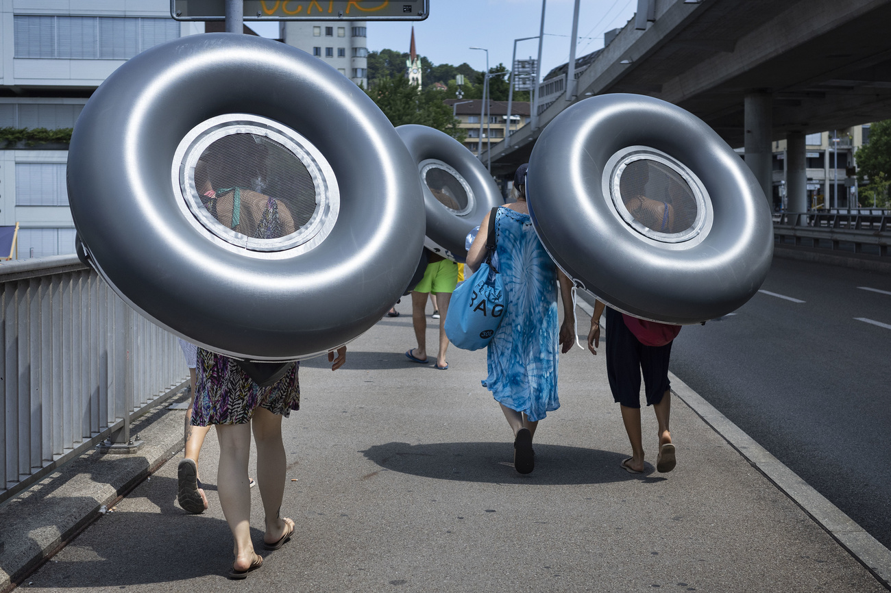 People carry rubber swim rings along a street.
