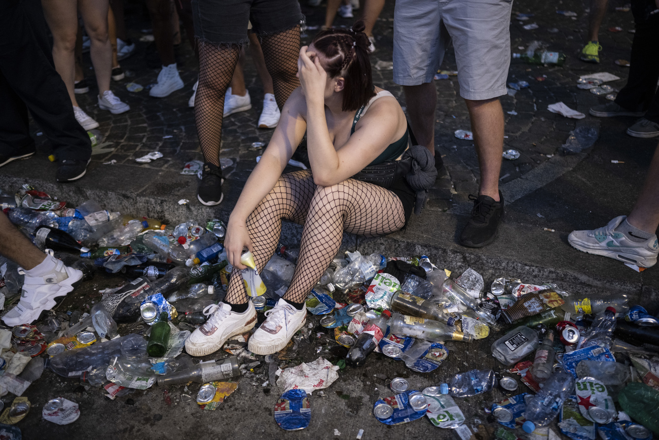 ragazza seduta su marciapiede in mezzo ai rifiuti lasciati dalla street parade