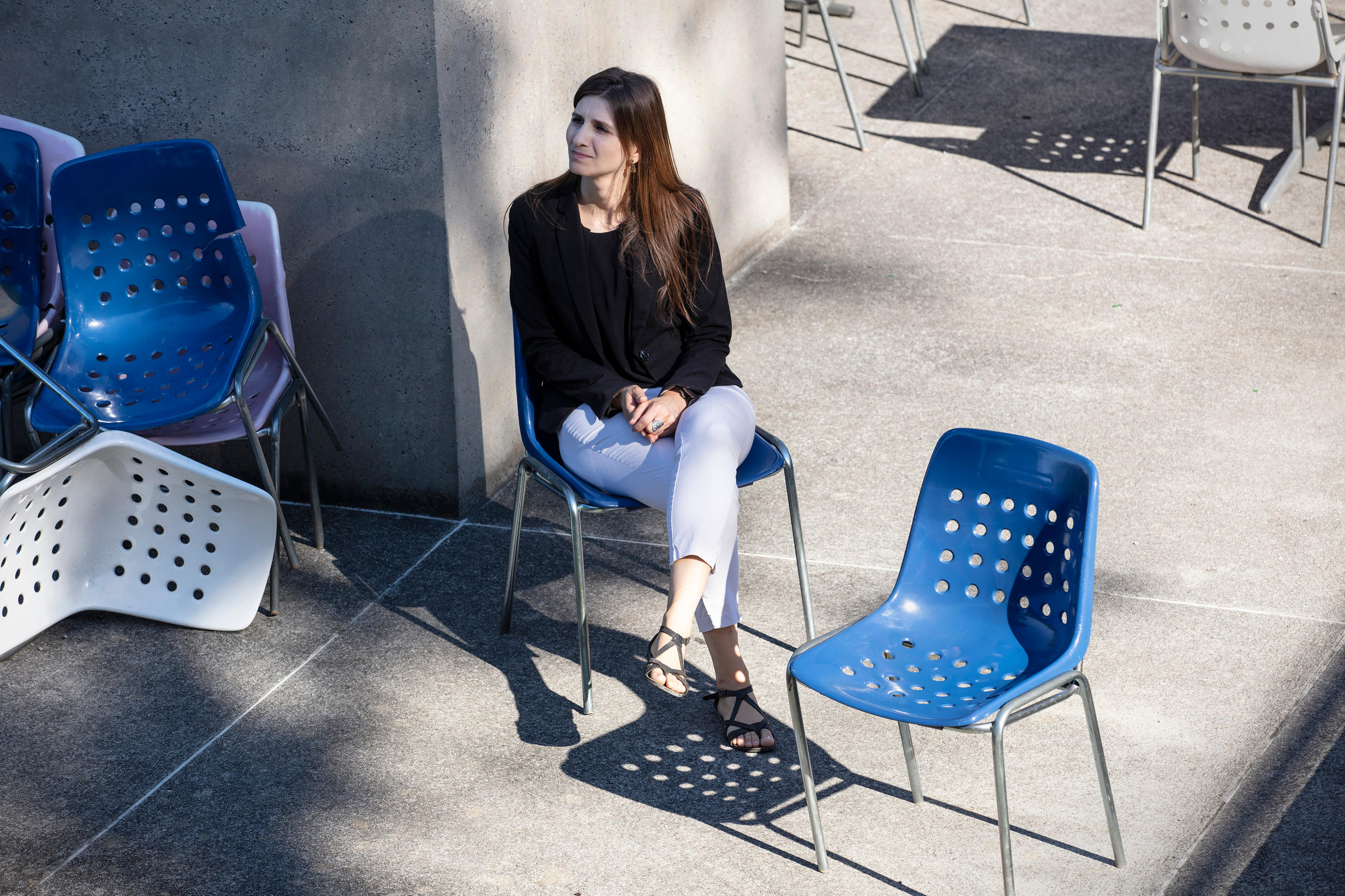 Femmes assise sur une chaise en plastique sur une terrasse en béton