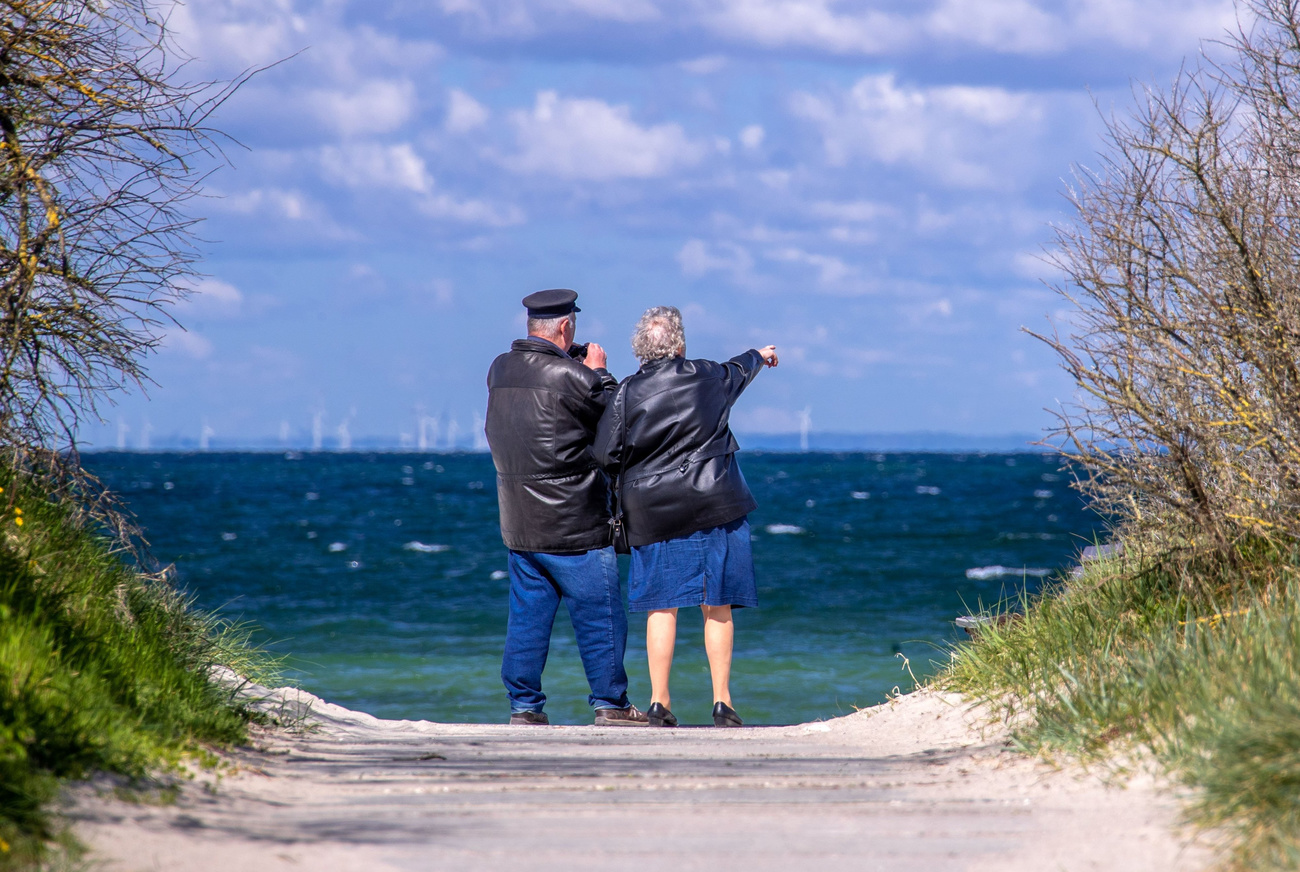 Coppia di pensionati indica l orizzonte.