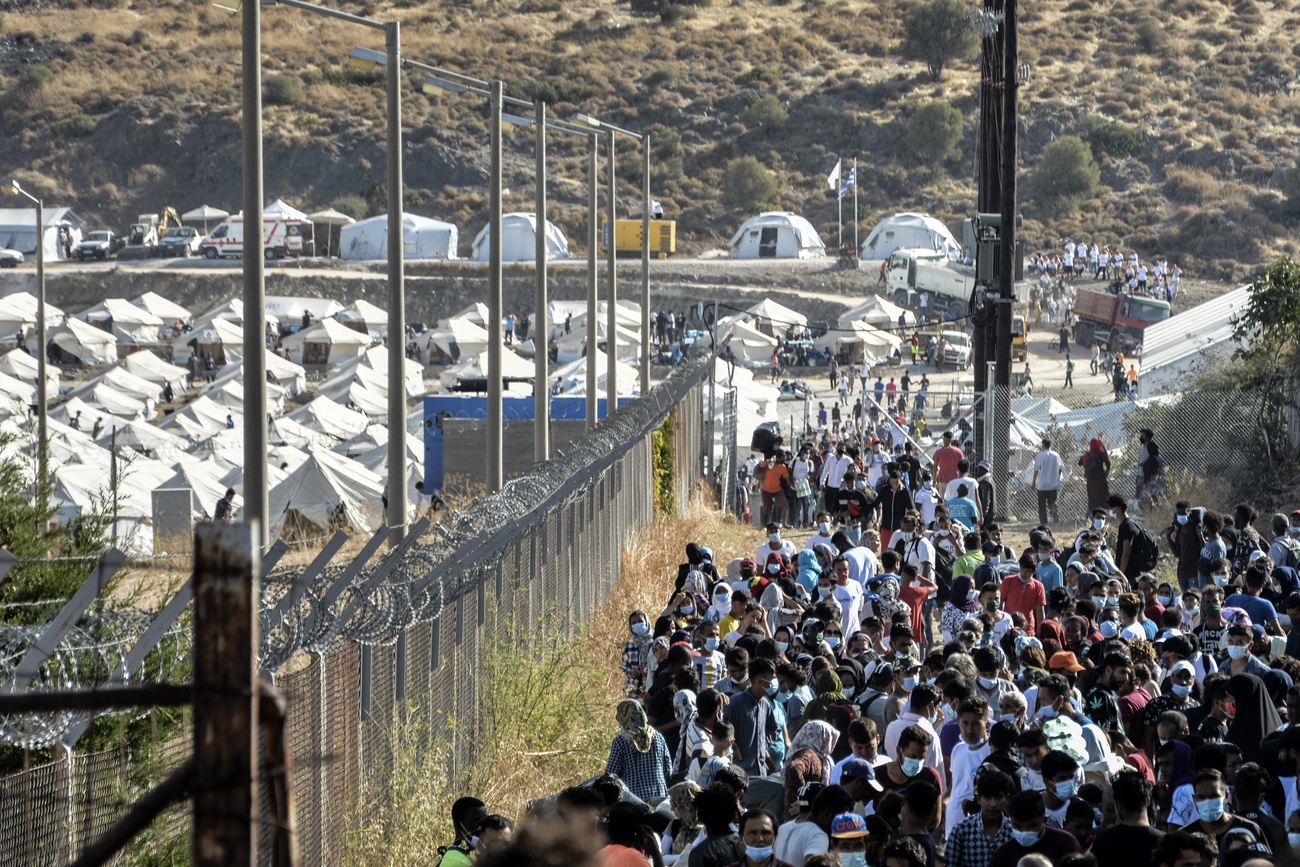 Tiendas de campaña y emigrantes junto a un alambrado y.