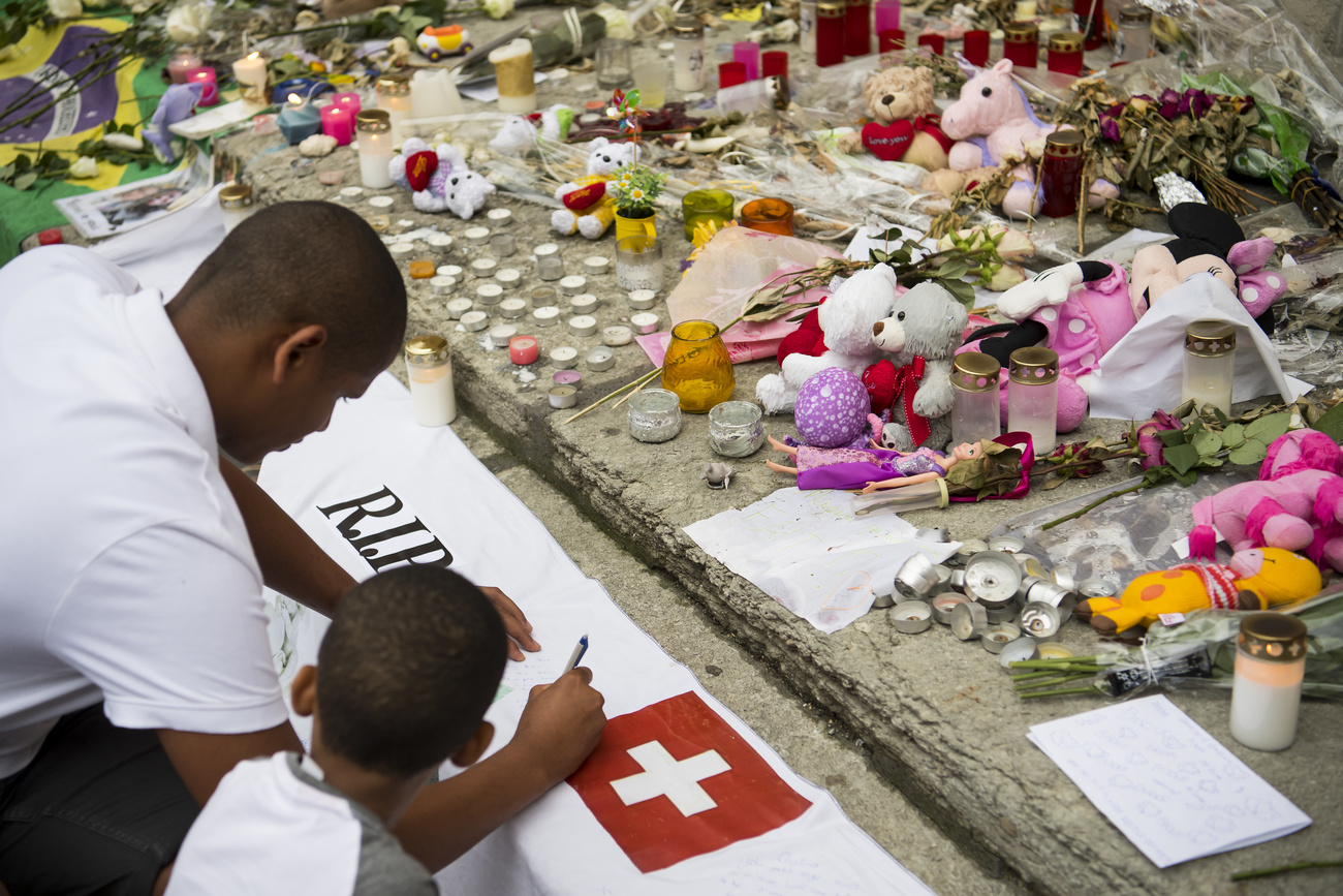 Deux personnes écrivent un mot sur une banderole en hommage aux victimes suisses de l attentat