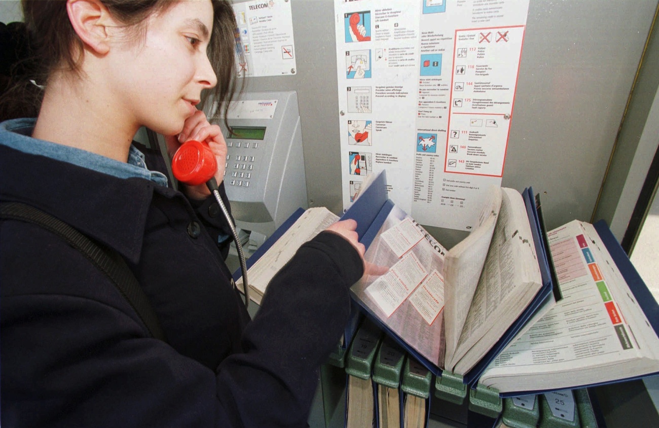 persona al telefono in cabina telefonica sfoglia elenco telefonico