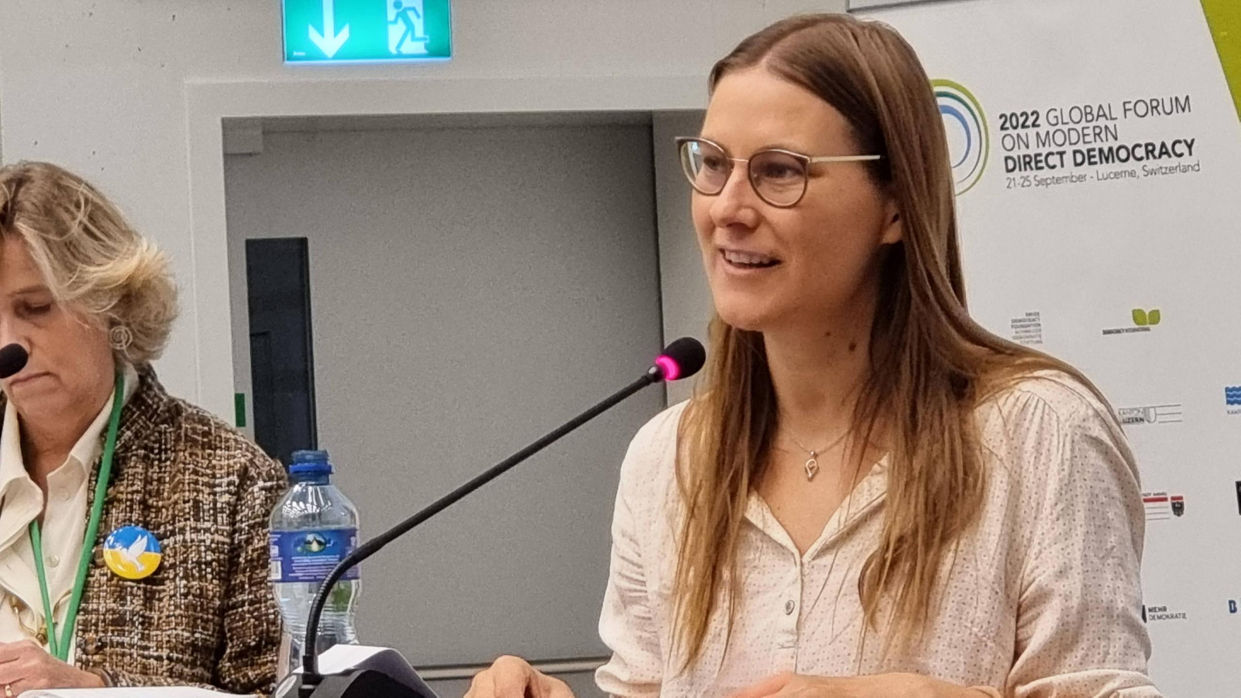 Junge Frau mit blonden Haaren spricht in ein Mikrofon