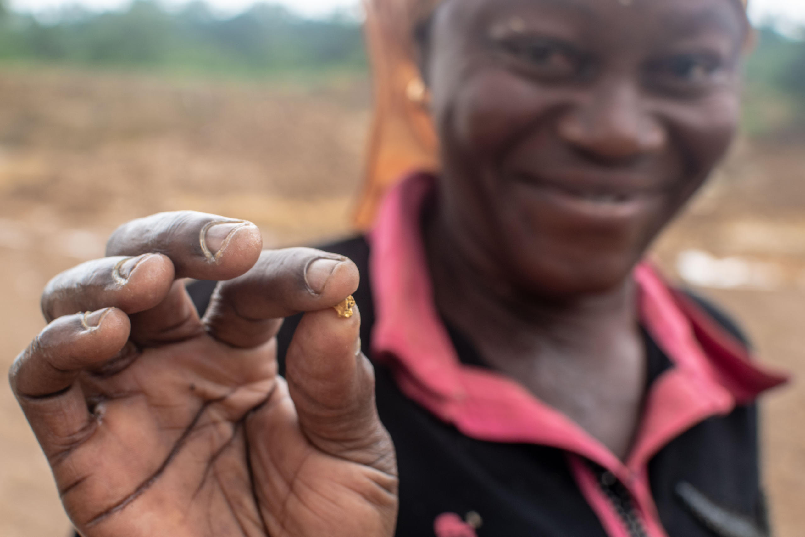 كتلة صلبة صغيرة من الذهب بين أصابع شخص من غانا