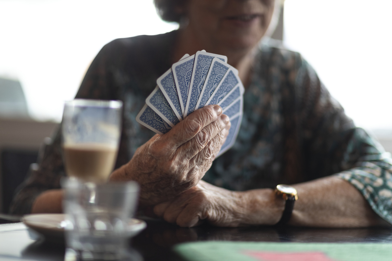 Elderly woman playing cards in Switzerland.